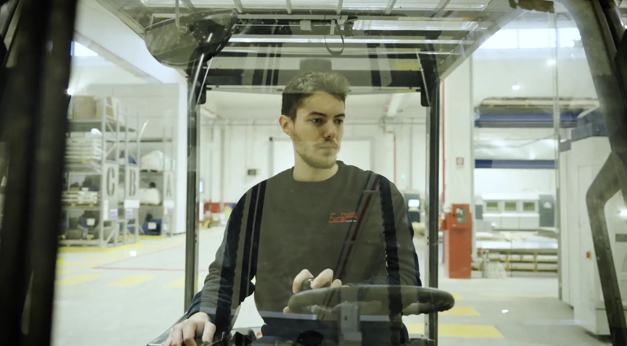 Une personne apparaît derrière l’enceinte transparente d’un équipement industriel.