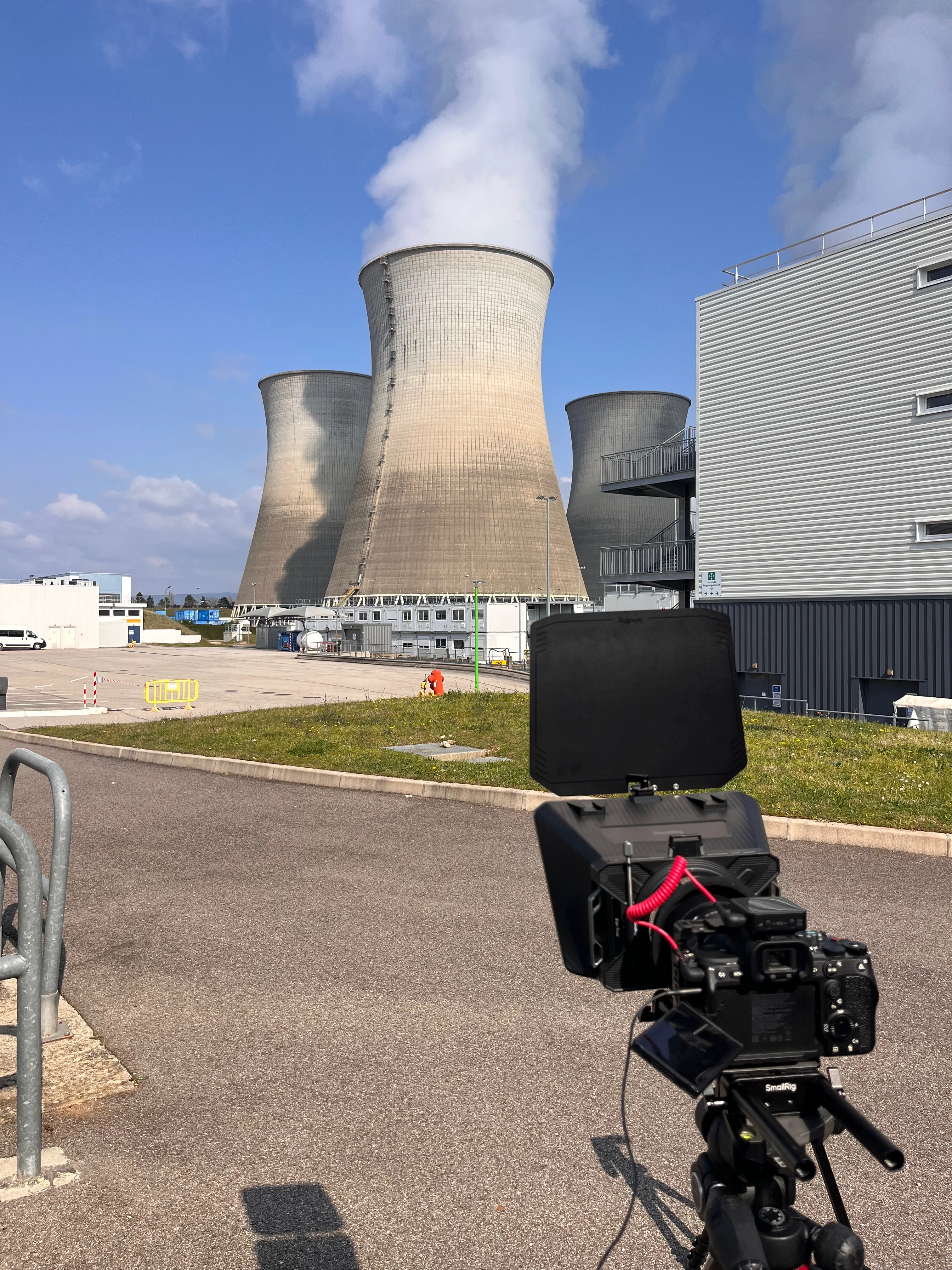 Caméra sur trépied devant une installation industrielle, illustration d’un tournage de produit en environnement professionnel.