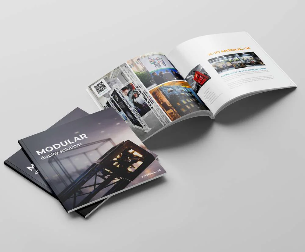 Brochure ouverte et brochure fermée présentant des solutions de displays modulaires sur une surface gris clair.