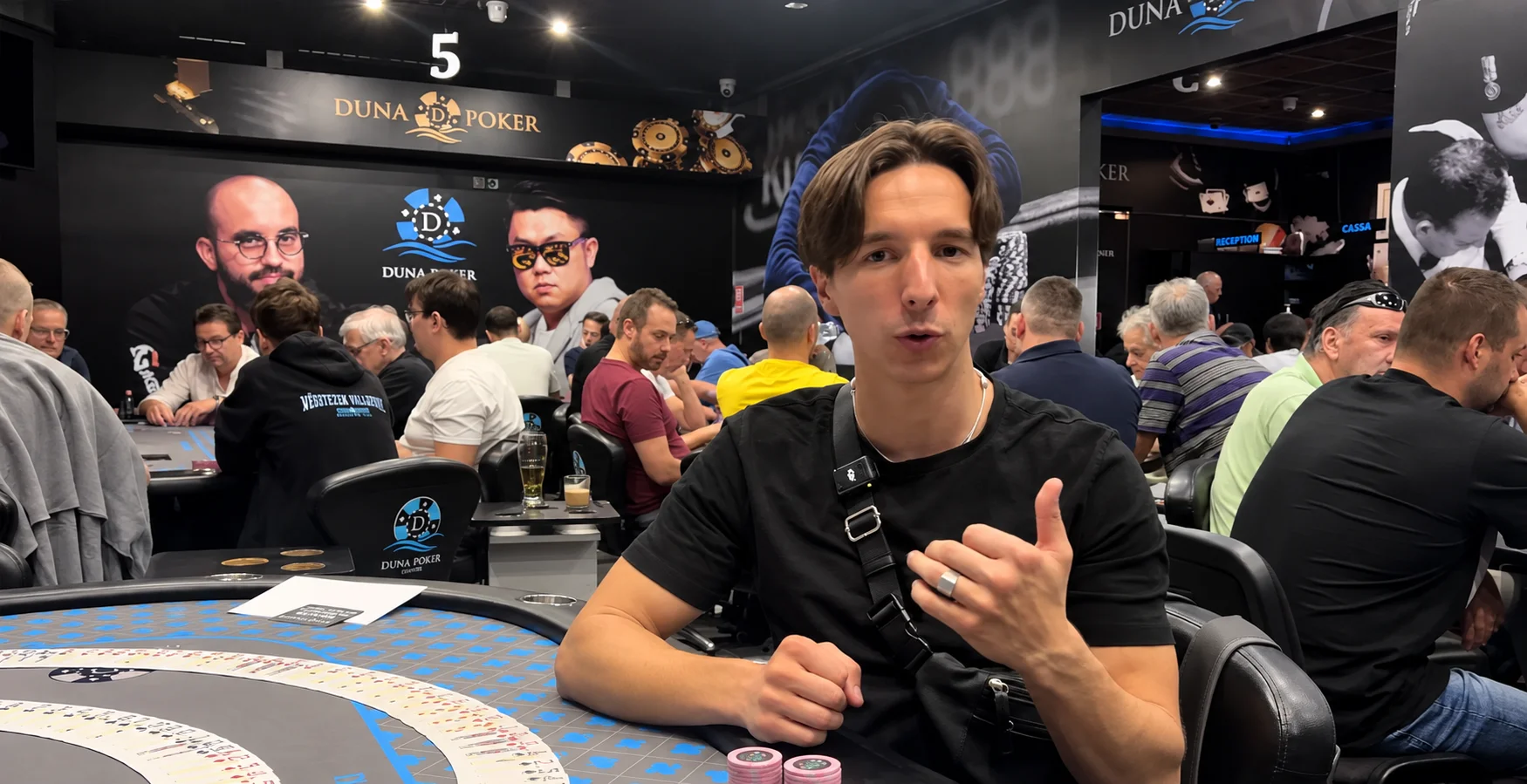 Salle de poker animée avec des joueurs assis autour de plusieurs tables.