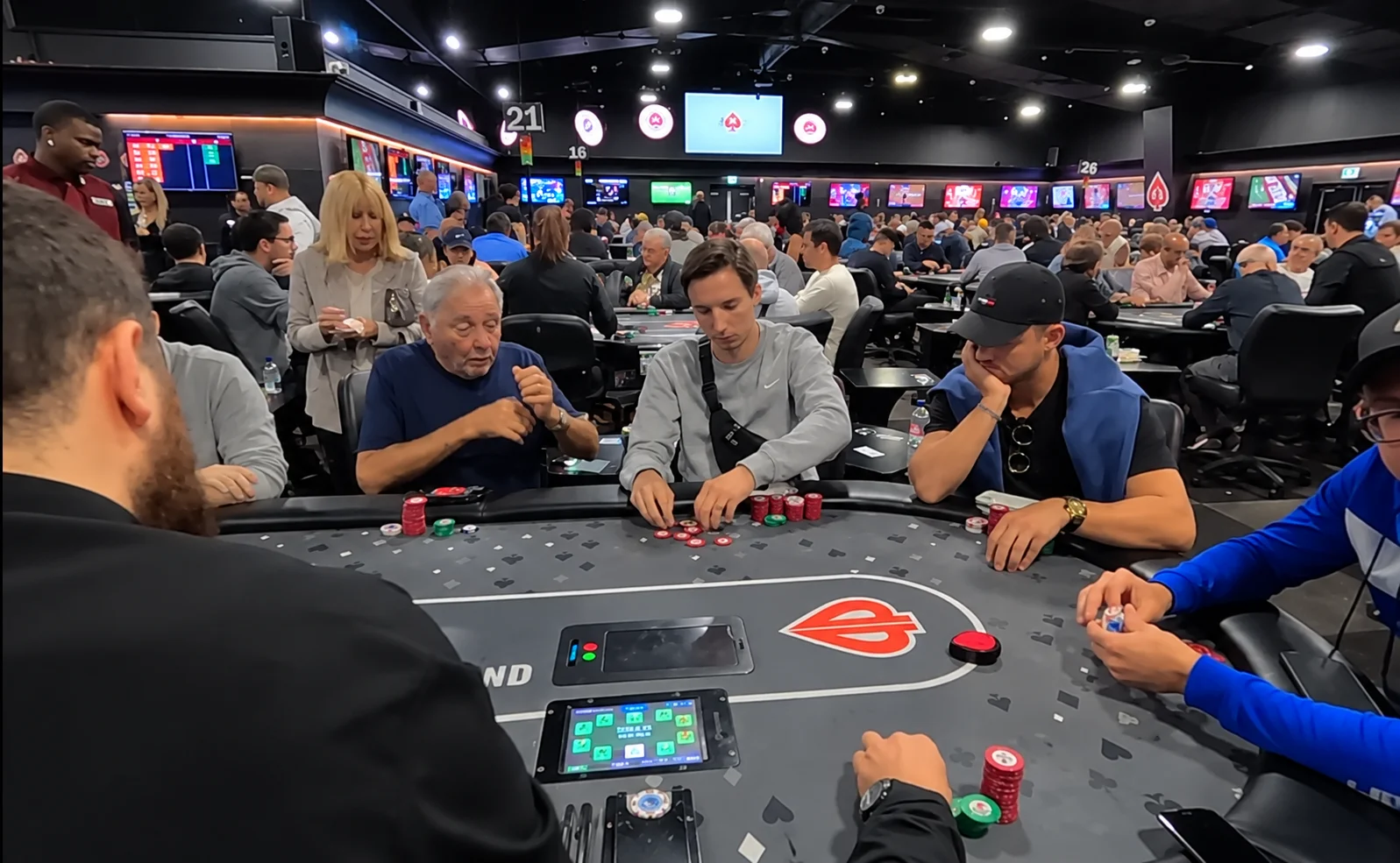 Des joueurs assis à une table de poker manipulent des jetons et des cartes.