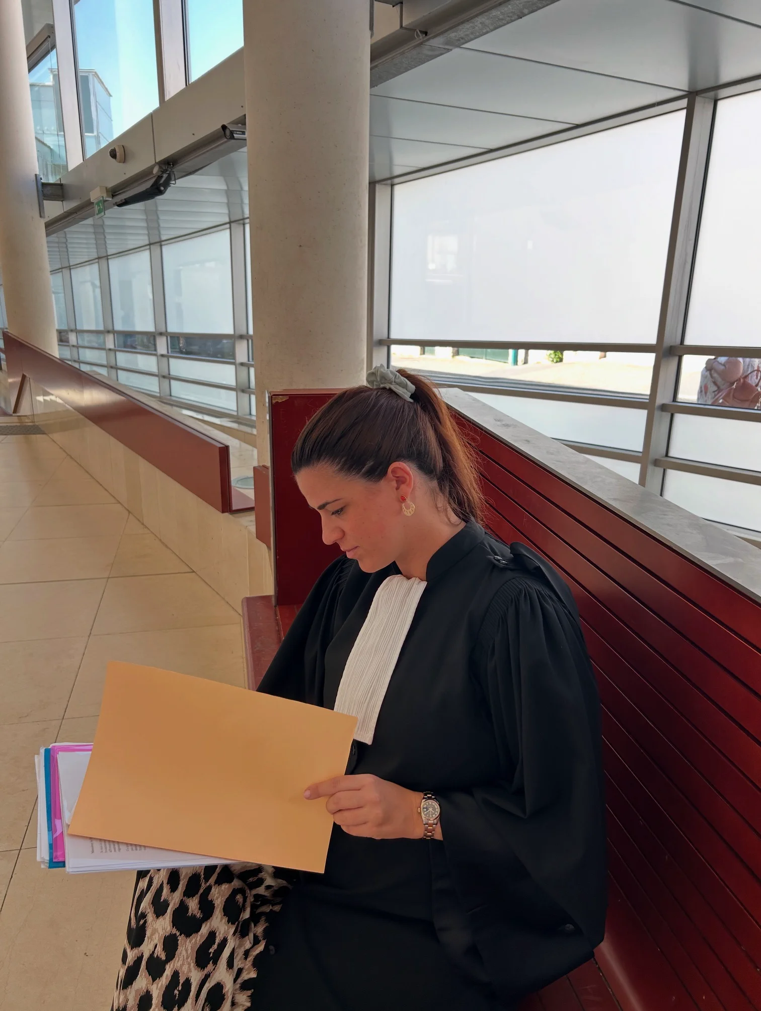 Personne assise consultant un dossier ouvert dans un intérieur clair vitré