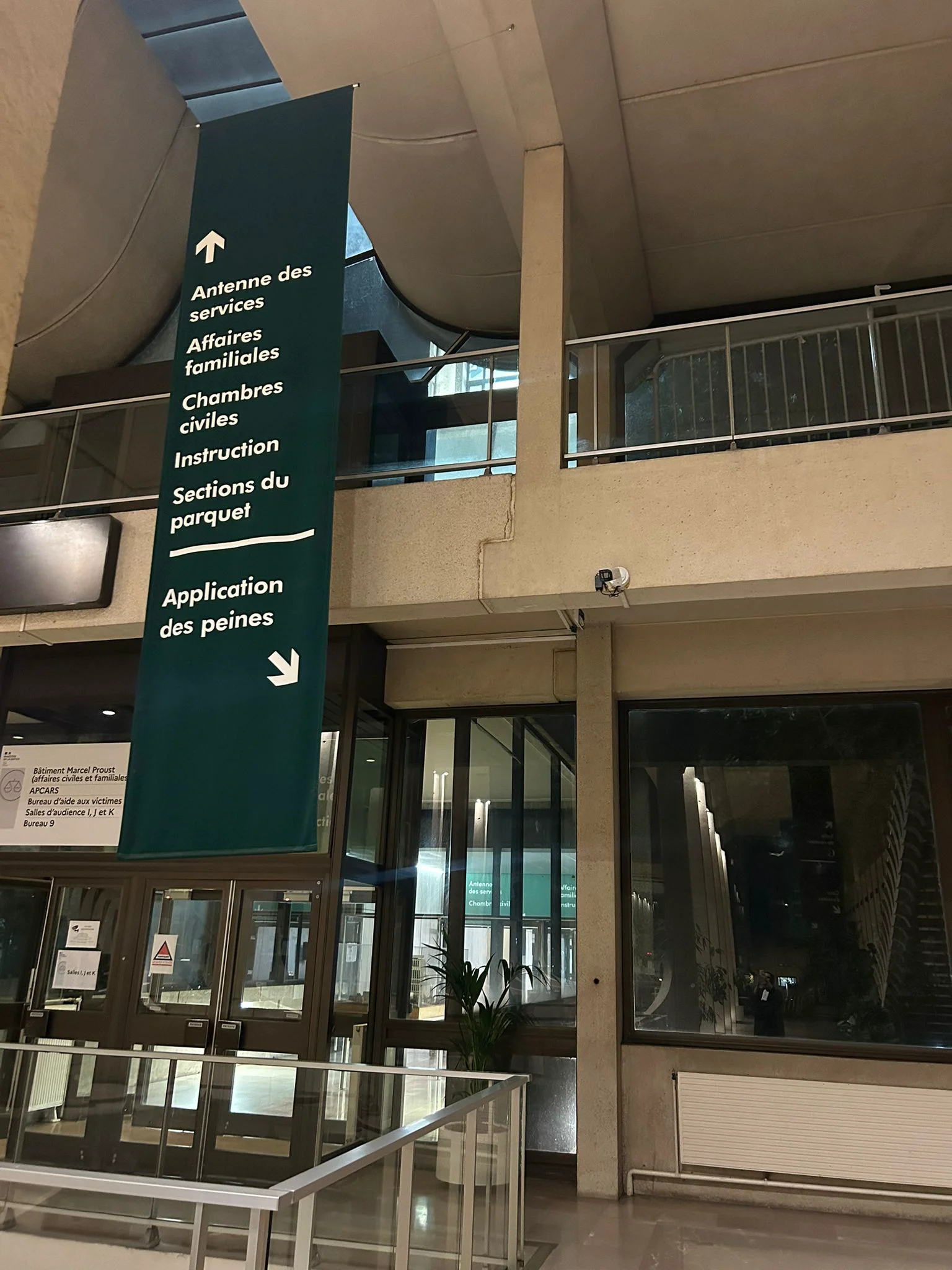 Un panneau directionnel en français indique notamment les affaires familiales dans le hall d’un bâtiment public.